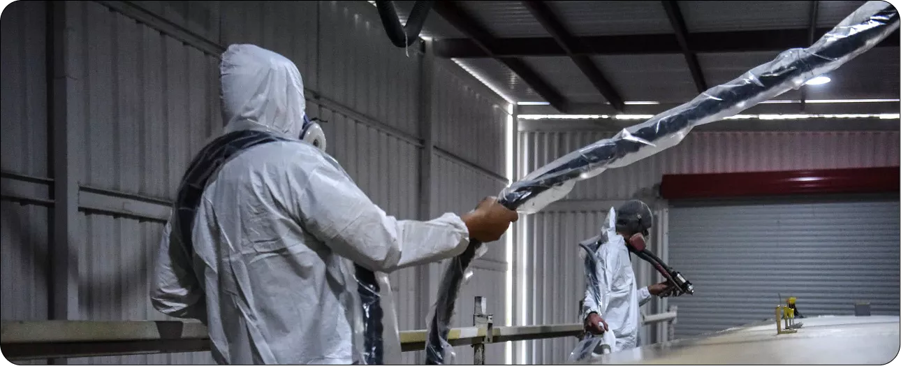 Two applicators spraying polyurea inside a steel building